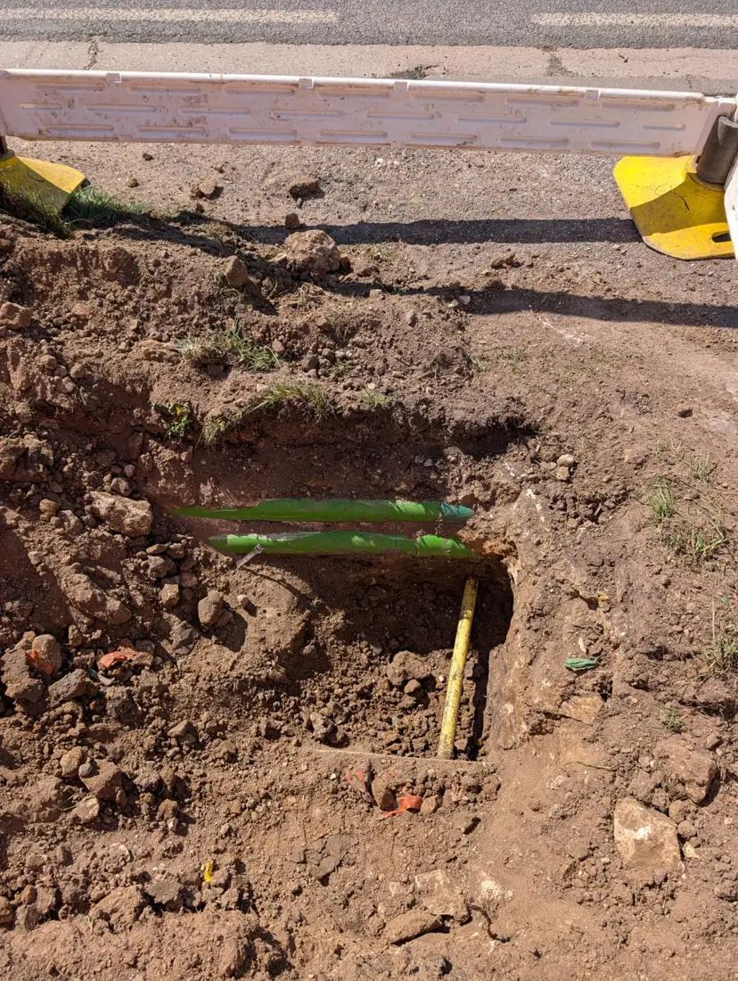 Trial hole exposing green ducts and a yellow gas pipe